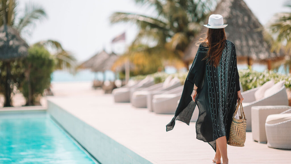 A traveler at a luxury resort walking past a pool in a tropical place